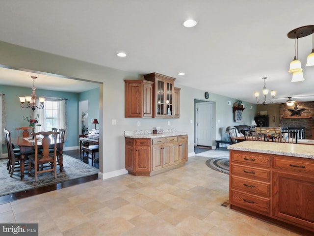 647 Warm Spring Rd, Chambersburg, PA 17202 - kitchen with a chandelier, brown cabinetry, glass insert cabinets, light stone countertops, and recessed lighting
