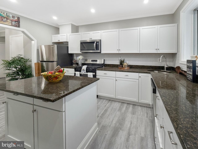 1180 Cleveland St, Baltimore, MD 21230 - kitchen with appliances with stainless steel finishes, light wood-style floors, white cabinets, tasteful backsplash, and ornamental molding
