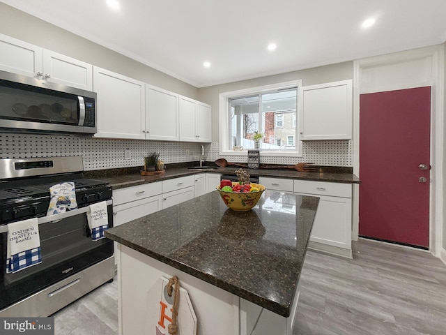 1180 Cleveland St, Baltimore, MD 21230 - kitchen with appliances with stainless steel finishes, decorative backsplash, white cabinets, light wood-style floors, and recessed lighting
