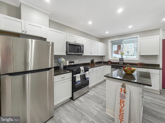 1180 Cleveland St, Baltimore, MD 21230 - kitchen with appliances with stainless steel finishes, ornamental molding, white cabinetry, light wood-style floors, and tasteful backsplash