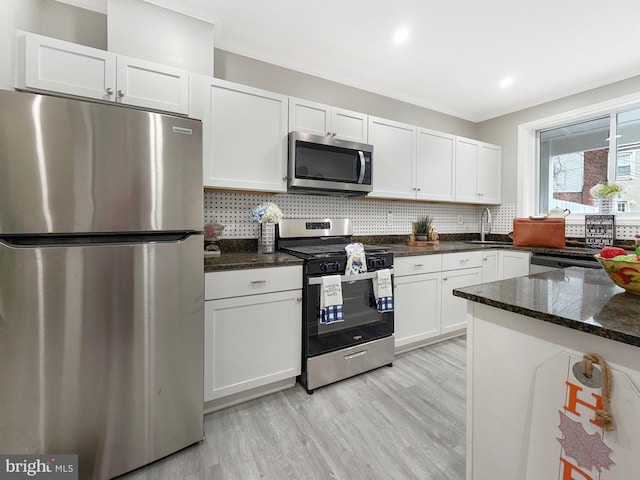 1180 Cleveland St, Baltimore, MD 21230 - kitchen featuring appliances with stainless steel finishes, white cabinets, backsplash, light wood-style floors, and ornamental molding