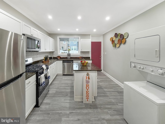 1180 Cleveland St, Baltimore, MD 21230 - kitchen with appliances with stainless steel finishes, stacked washer / dryer, backsplash, crown molding, and a center island