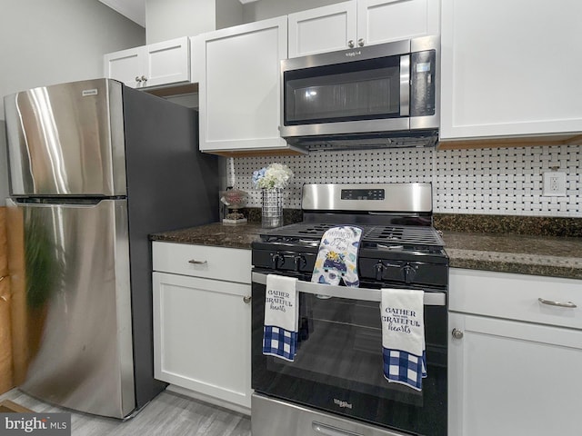 1180 Cleveland St, Baltimore, MD 21230 - kitchen featuring appliances with stainless steel finishes, white cabinets, decorative backsplash, dark stone countertops, and light wood-style floors