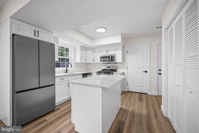 400 Reservoir St, Trenton, NJ 08618 - kitchen featuring appliances with stainless steel finishes, white cabinets, light countertops, wood finished floors, and a center island