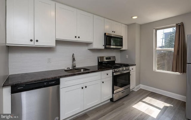 332 E Conestoga Rd, Wayne, PA 19087 - kitchen with appliances with stainless steel finishes, wood finished floors, white cabinets, decorative backsplash, and dark stone countertops