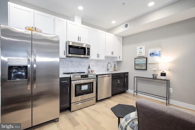 505 Kennedy St NW Unit B02, Washington, DC 20011 - kitchen featuring stainless steel appliances, decorative backsplash, light wood-style floors, white cabinetry, and light countertops