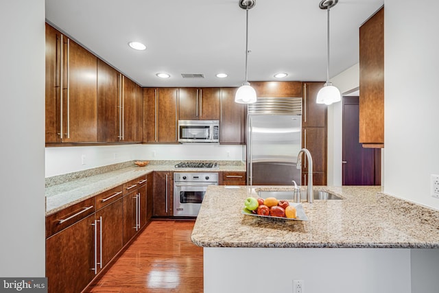 12500 Park Potomac Ave Unit 409, Potomac, MD 20854 - kitchen with appliances with stainless steel finishes, a peninsula, light stone countertops, light wood-style floors, and recessed lighting