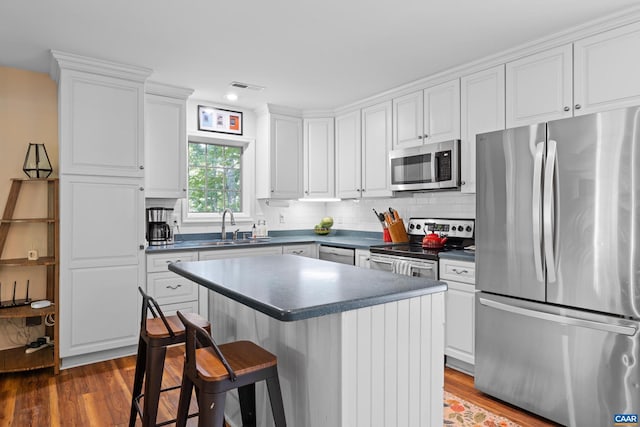 295 Homestead Ln, Charlottesville, VA 22902 - kitchen featuring stainless steel appliances, wood finished floors, a kitchen bar, dark countertops, and white cabinetry