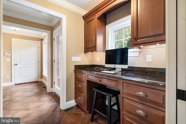 3054 Jordan Rd, Orefield, PA 18069 - kitchen with ornamental molding, built in desk, dark tile patterned flooring, brown cabinets, and dark stone counters