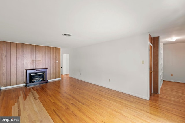 412 Fairview Ave, Winchester, VA 22601 - unfurnished living room featuring light wood-style flooring, a glass covered fireplace, and wooden walls