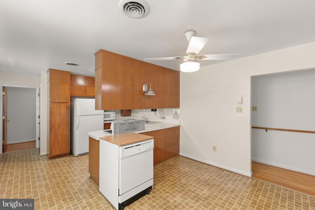 412 Fairview Ave, Winchester, VA 22601 - kitchen with white appliances, light countertops, brown cabinets, ceiling fan, and a peninsula