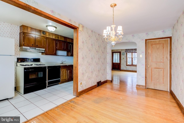 257 Westpark Ln, Clifton Heights, PA 19018 - kitchen with white appliances, under cabinet range hood, wallpapered walls, light wood finished floors, and a chandelier
