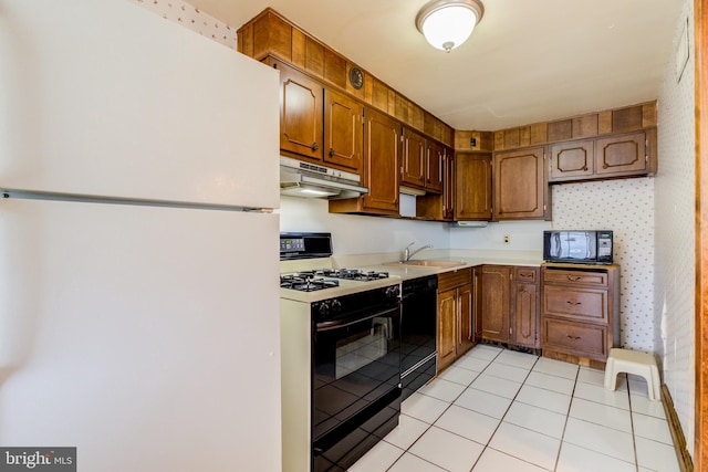 257 Westpark Ln, Clifton Heights, PA 19018 - kitchen with black appliances, under cabinet range hood, light countertops, light tile patterned floors, and brown cabinets