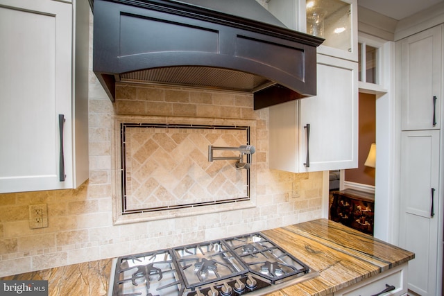 3879 Charter Club Dr, Doylestown, PA 18902 - kitchen with stainless steel gas cooktop, exhaust hood, decorative backsplash, white cabinetry, and glass insert cabinets