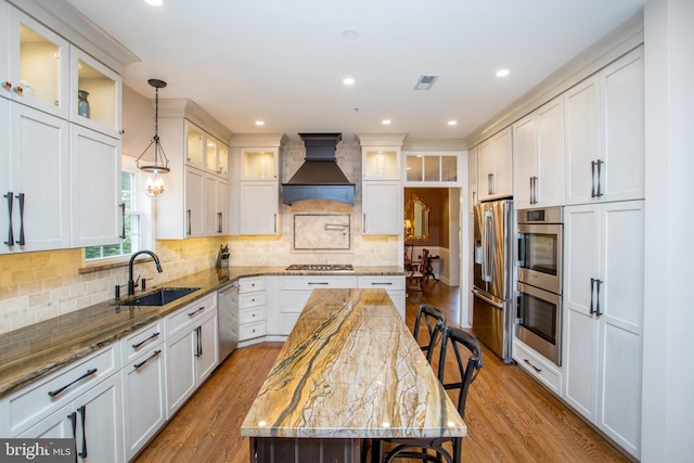3879 Charter Club Dr, Doylestown, PA 18902 - kitchen featuring premium range hood, appliances with stainless steel finishes, wood finished floors, a breakfast bar, and light stone counters
