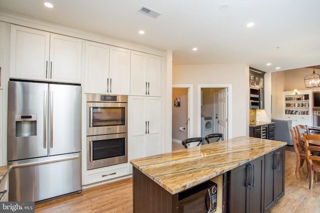 3879 Charter Club Dr, Doylestown, PA 18902 - kitchen featuring appliances with stainless steel finishes, washer / clothes dryer, light wood-type flooring, light stone countertops, and recessed lighting