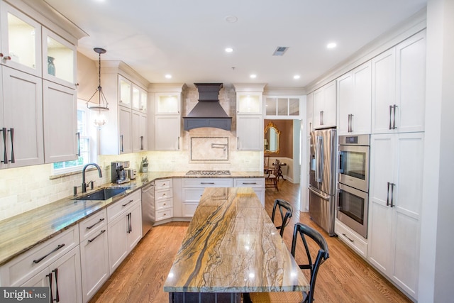 3879 Charter Club Dr, Doylestown, PA 18902 - kitchen with custom range hood, stainless steel appliances, light wood-style flooring, light stone counters, and decorative backsplash