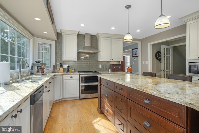 11603 Auburn Grove Ct, Reston, VA 20194 - kitchen with wall chimney range hood, stainless steel appliances, light wood-type flooring, decorative light fixtures, and tasteful backsplash