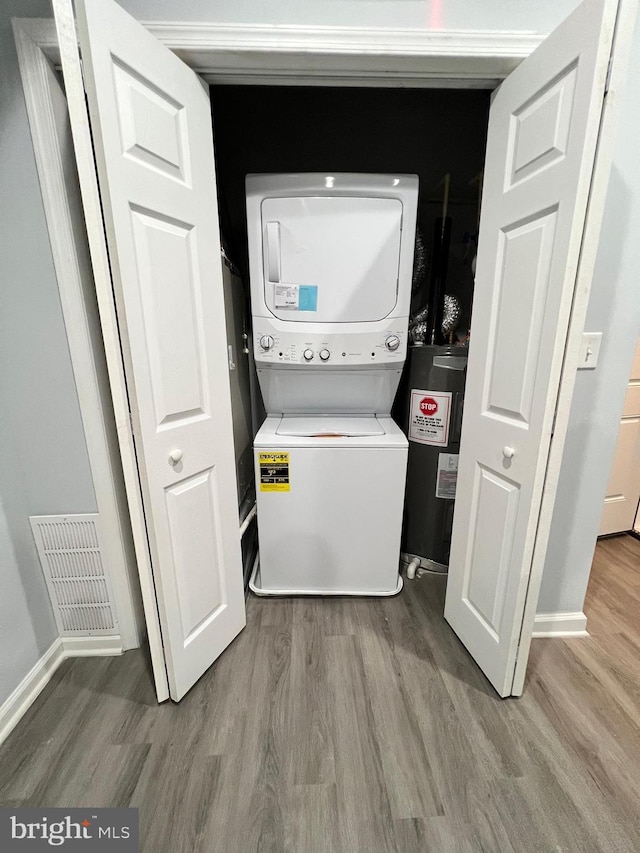 1107 N Fulton Ave, Baltimore, MD 21217 - laundry room featuring estacked washer and dryer, wood finished floors, and electric water heater