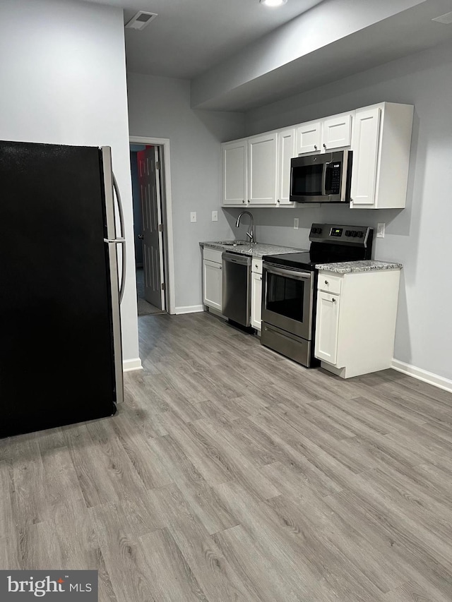 1107 N Fulton Ave, Baltimore, MD 21217 - kitchen featuring stainless steel appliances, light wood-style flooring, white cabinets, and light stone countertops