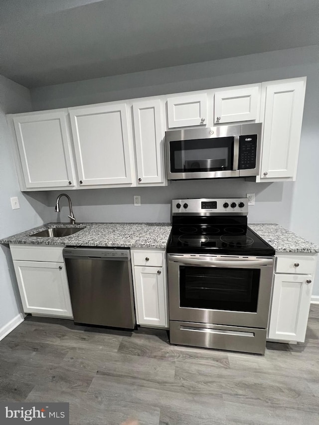 1107 N Fulton Ave, Baltimore, MD 21217 - kitchen featuring stainless steel appliances, white cabinets, light stone counters, and light wood-style flooring