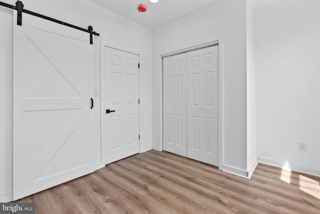 3216 N Randolph St, Philadelphia, PA 19140 - unfurnished bedroom featuring a barn door, light wood-type flooring, and a closet