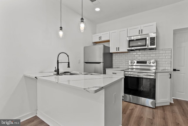 3216 N Randolph St, Philadelphia, PA 19140 - kitchen with stainless steel appliances, wood finished floors, white cabinetry, decorative backsplash, and a peninsula