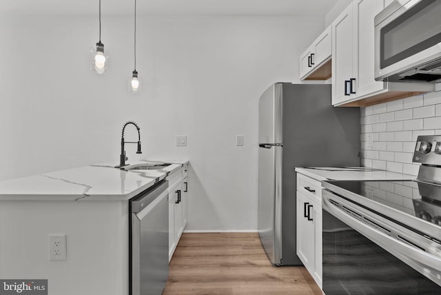 3216 N Randolph St, Philadelphia, PA 19140 - kitchen with stainless steel appliances, a peninsula, backsplash, white cabinetry, and light stone countertops
