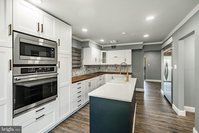 30 Scott Ct, Chesterbrook, PA 19087 - kitchen featuring built in appliances, decorative backsplash, crown molding, a kitchen island with sink, and glass insert cabinets