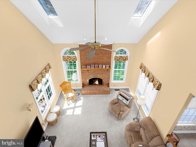 1509 Winfields Ln, Gambrills, MD 21054 - carpeted living room featuring a skylight, a ceiling fan, a high ceiling, and a brick fireplace