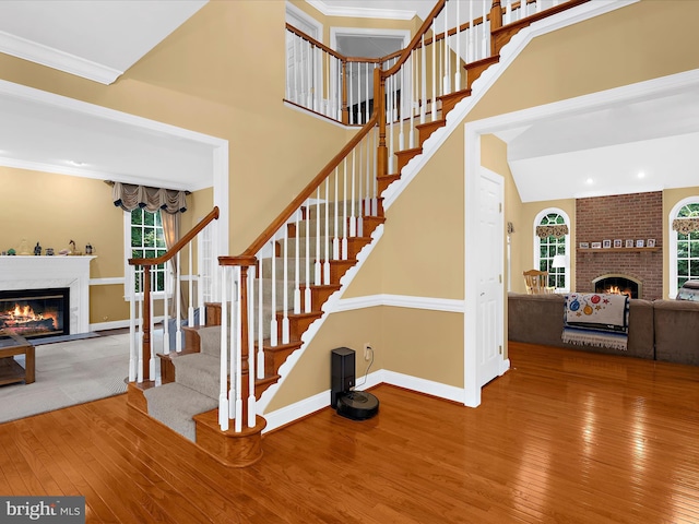 1509 Winfields Ln, Gambrills, MD 21054 - stairs featuring a brick fireplace, wood-type flooring, healthy amount of natural light, a towering ceiling, and ornamental molding