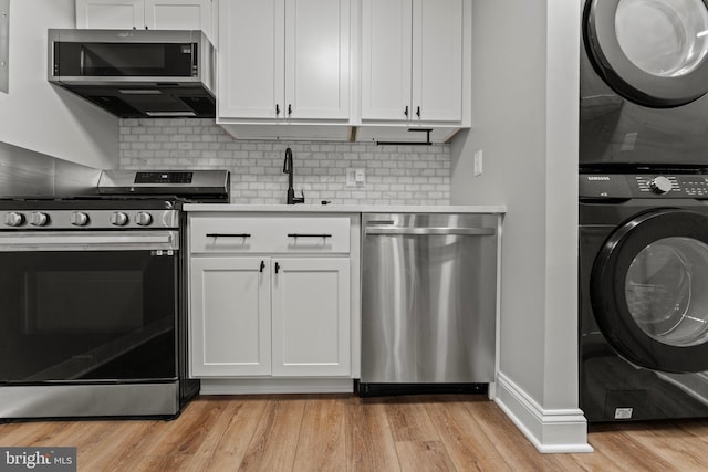 8677 Greenbelt Rd Unit 201, Greenbelt, MD 20770 - kitchen with appliances with stainless steel finishes, stacked washer and clothes dryer, light wood-style flooring, light countertops, and white cabinetry