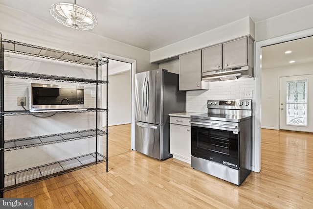 7119 Sea Cliff Rd, Mclean, VA 22101 - kitchen featuring stainless steel appliances, under cabinet range hood, light wood-style floors, gray cabinetry, and tasteful backsplash
