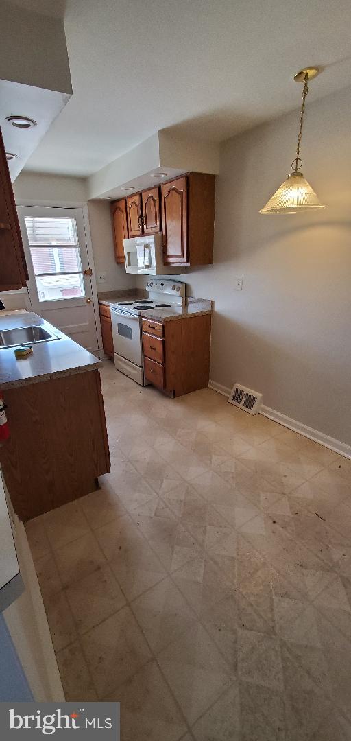 200 Baldwin Ave, Ridley Park, PA 19078 - kitchen with white appliances, brown cabinets, and decorative light fixtures