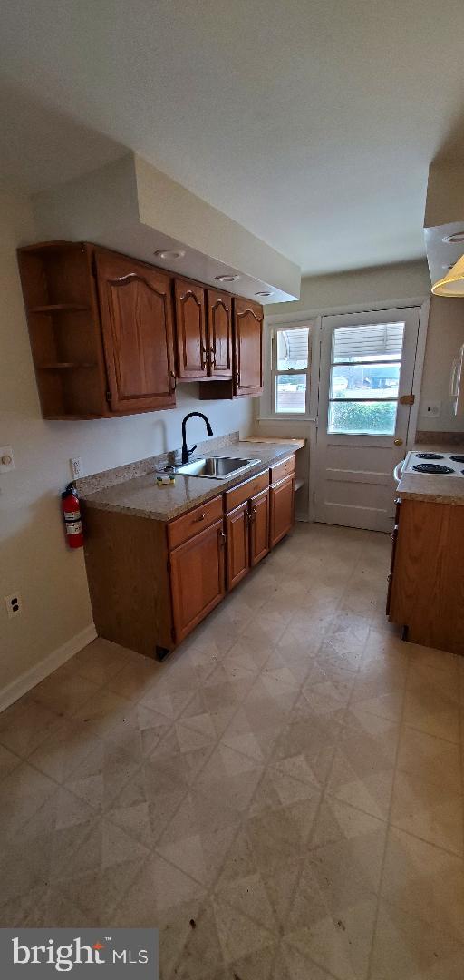 200 Baldwin Ave, Ridley Park, PA 19078 - kitchen featuring light countertops, brown cabinets, open shelves, light floors, and range hood