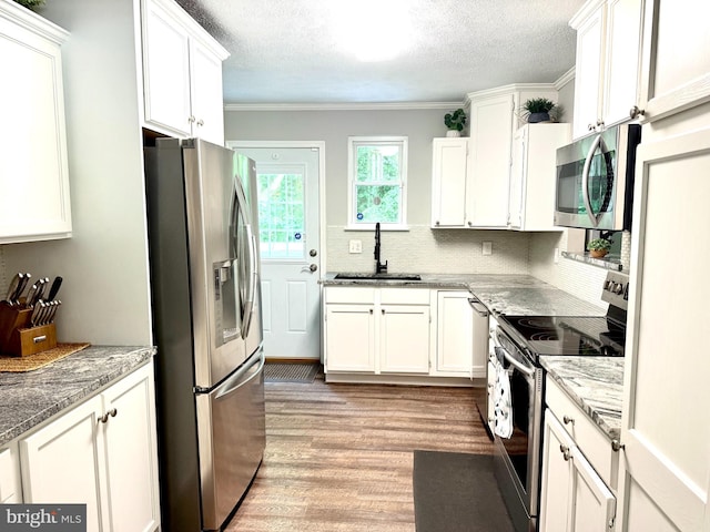 4123 Cassell Blvd, Prince Frederick, MD 20678 - kitchen featuring appliances with stainless steel finishes, light wood-style floors, white cabinetry, tasteful backsplash, and a textured ceiling