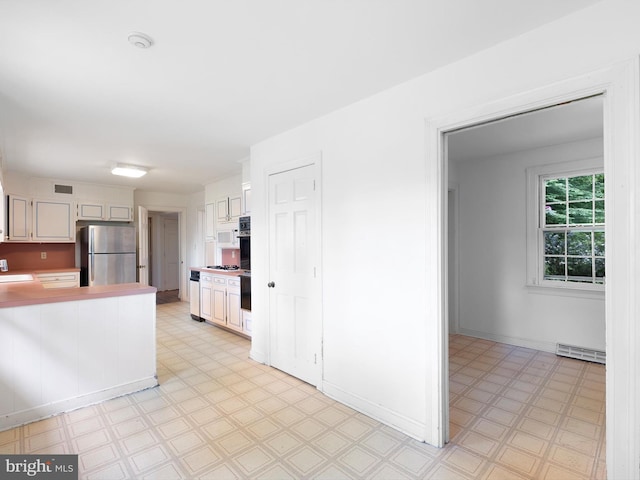 407 Owls Nest Rd, Wilmington, DE 19807 - kitchen with freestanding refrigerator, light floors, light countertops, a peninsula, and white cabinetry