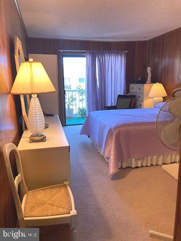 718 Mooring Rd Unit B203, Ocean City, MD 21842 - bedroom with wood walls, carpet floors, access to exterior, and a textured ceiling