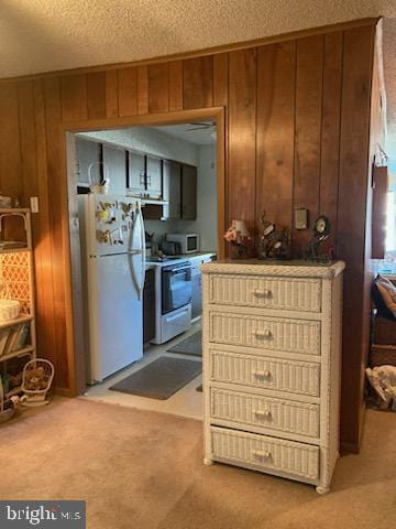 718 Mooring Rd Unit B203, Ocean City, MD 21842 - kitchen featuring white appliances, wooden walls, light colored carpet, and a textured ceiling