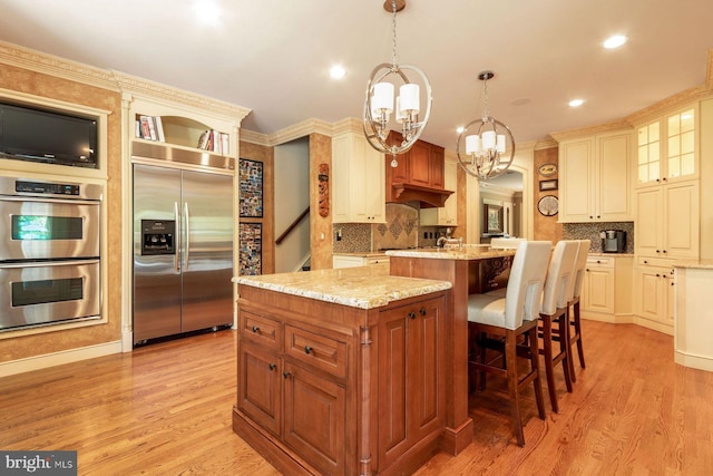 3500 Windy Bush Rd, New Hope, PA 18938 - kitchen with appliances with stainless steel finishes, a chandelier, a center island with sink, light wood-style floors, and light stone counters