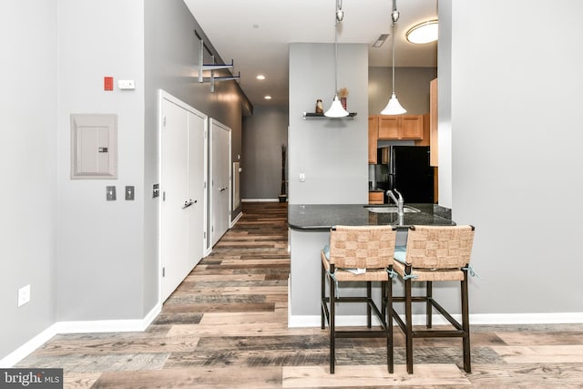 355 I St SW Unit S-102, Washington, DC 20024 - kitchen with freestanding refrigerator, wood finished floors, electric panel, dark countertops, and a breakfast bar area