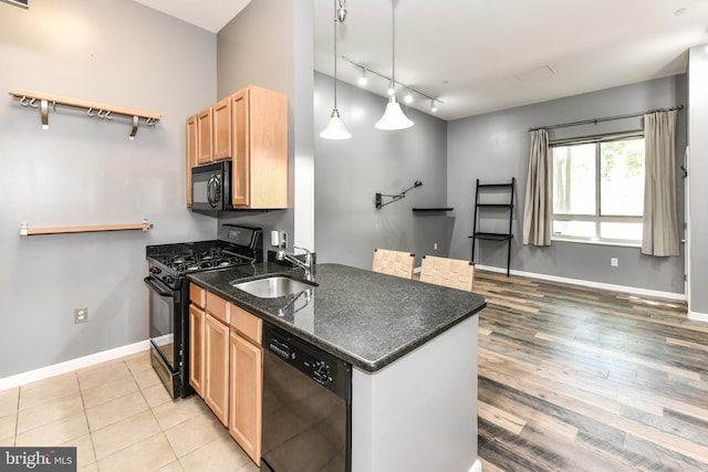 355 I St SW Unit S-102, Washington, DC 20024 - kitchen featuring black appliances, light brown cabinets, track lighting, light wood-style flooring, and dark stone countertops