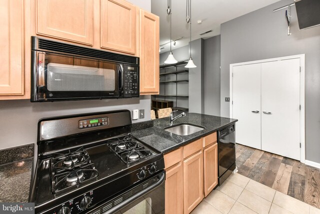355 I St SW Unit S-102, Washington, DC 20024 - kitchen featuring black appliances, light brown cabinets, light wood-style floors, and dark stone counters