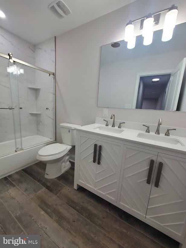 258 Ridge Rd, Browns Mills, NJ 08015 - bathroom featuring double vanity, wood finished floors, and bath / shower combo with glass door