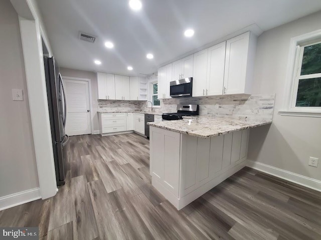 258 Ridge Rd, Browns Mills, NJ 08015 - kitchen with appliances with stainless steel finishes, a peninsula, tasteful backsplash, dark wood-style flooring, and white cabinets