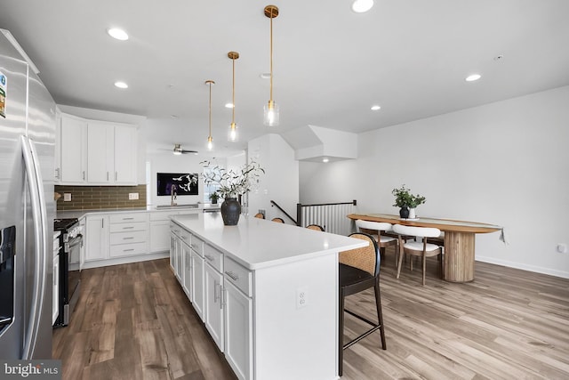 1025 Overlook Way, Laurel, MD 20707 - kitchen featuring range, a kitchen breakfast bar, stainless steel fridge, wood finished floors, and a kitchen island
