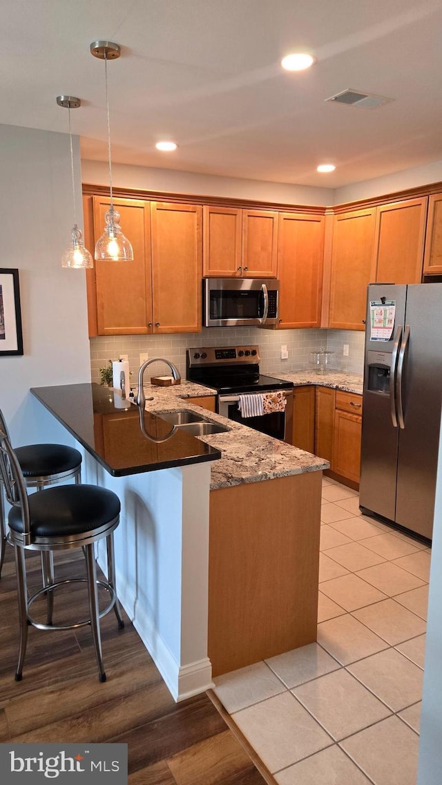 1000 Fountainview Cir Unit 1406, Newark, DE 19713 - kitchen with appliances with stainless steel finishes, a peninsula, decorative backsplash, pendant lighting, and brown cabinetry