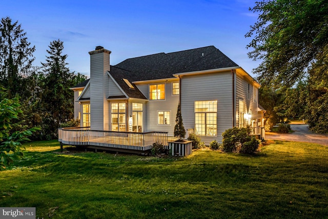 501 Van Lears Run, Villanova, PA 19085 - back of property at dusk with a deck, a lawn, a chimney, and roof with shingles