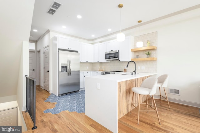 3116 Clifford St Unit 2, Philadelphia, PA 19121 - kitchen featuring appliances with stainless steel finishes, a kitchen bar, a peninsula, decorative backsplash, and light wood-style flooring
