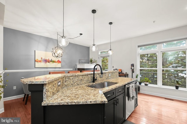 1506 Stack St, Baltimore, MD 21230 - kitchen featuring dishwasher, light wood finished floors, dark cabinetry, a kitchen island with sink, and decorative light fixtures